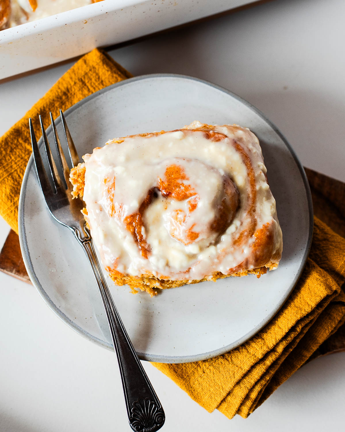 top view of an iced sweet potato cinnamon roll on a plate