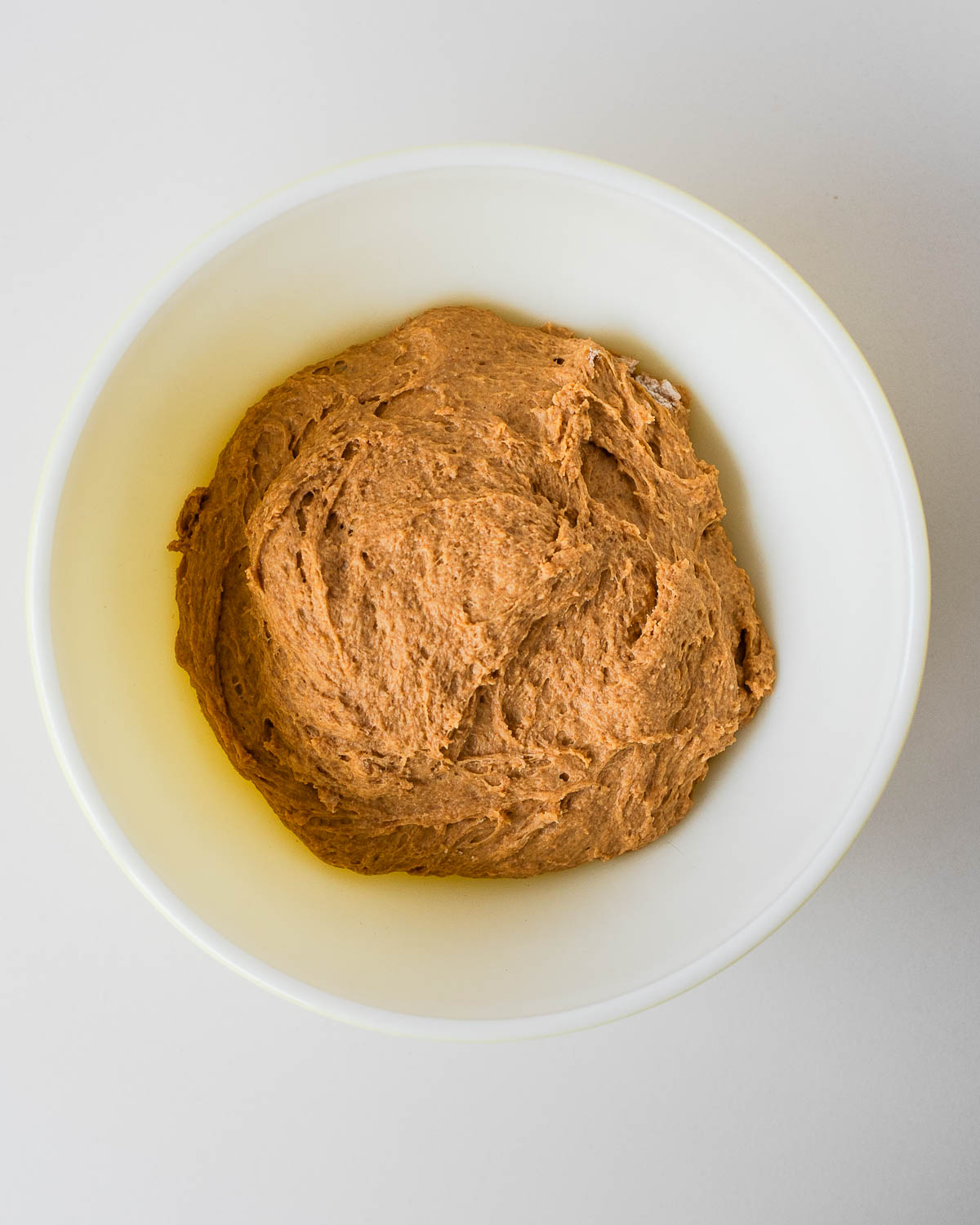 Sweet potato cinnamon roll dough mixed in a bowl, ready to rise