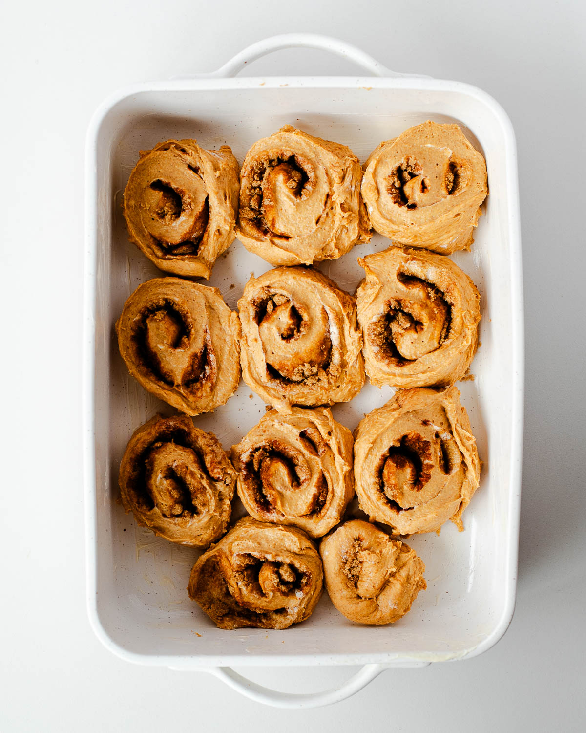 Unbaked sweet potato cinnamon rolls arranged in a baking dish before refrigerating overnight