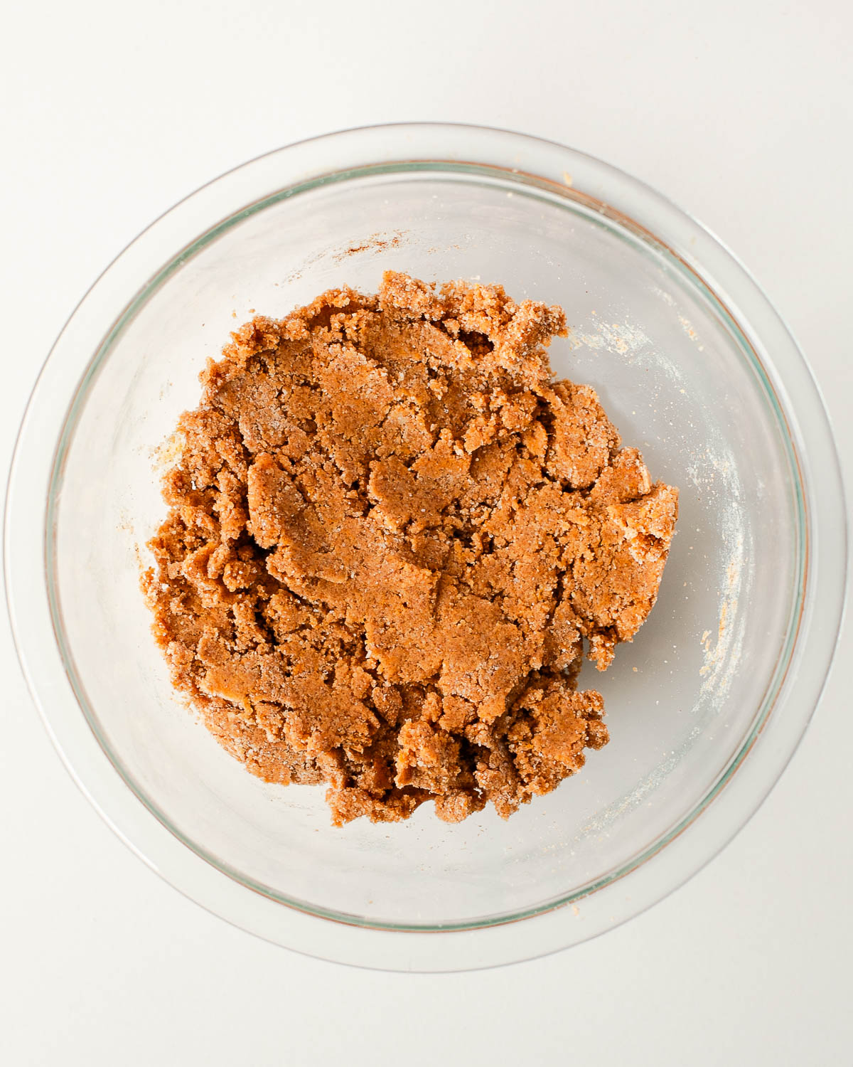 Sweet potato snickerdoodle cookie dough mixed in a clear glass bowl before rolling in cinnamon sugar