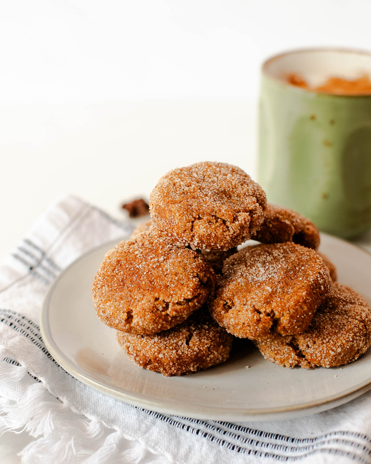 Soft sweet potato snickerdoodle cookies with cinnamon sugar coating stacked on a plate