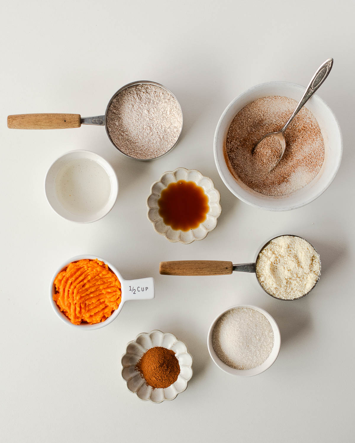 Ingredients for sweet potato snickerdoodle cookies including mashed sweet potato, almond flour, whole wheat flour, cinnamon, sugar, coconut oil, and vanilla extract