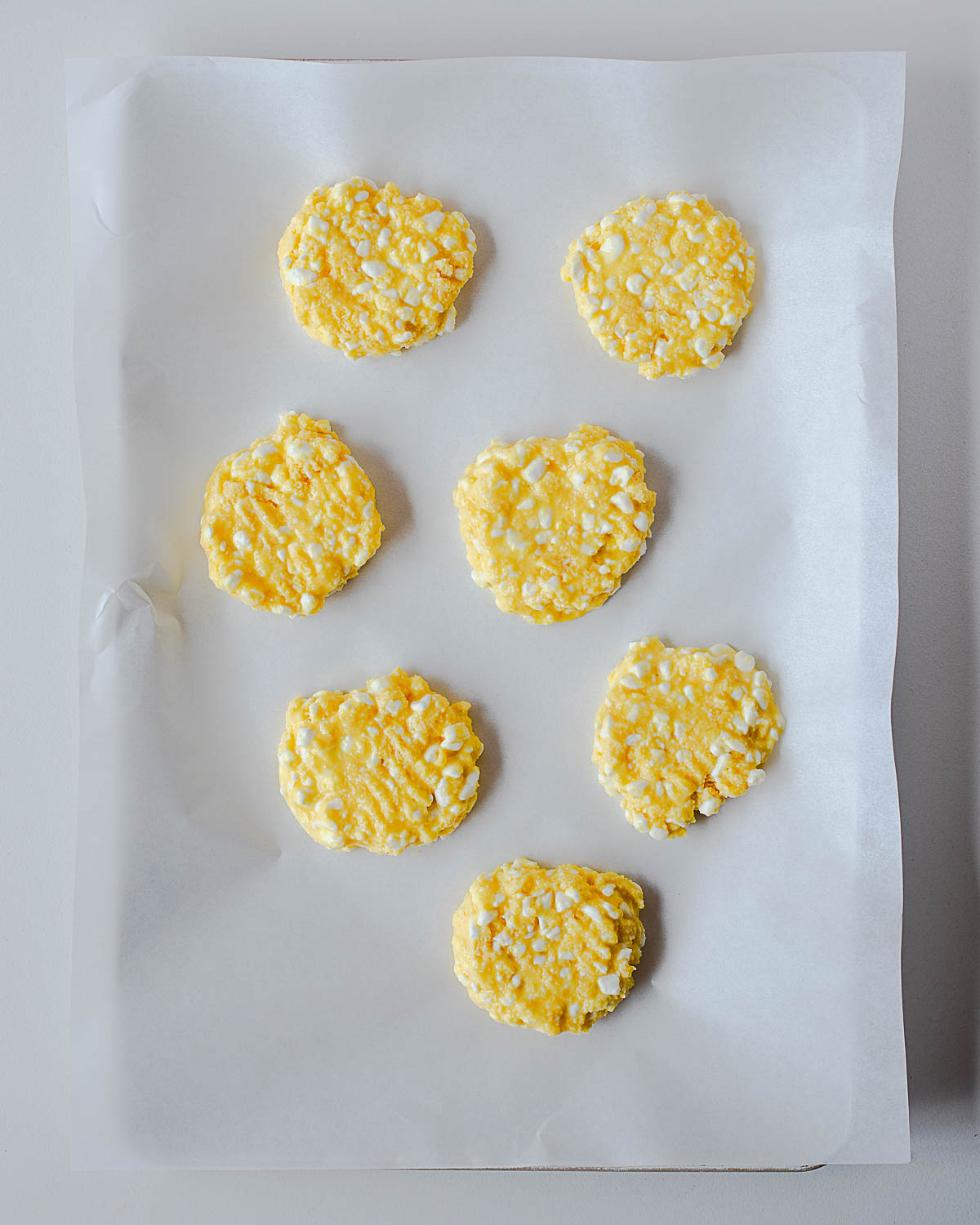 Scoops of cottage cheese pizza crust batter shaped into rounds on a parchment-lined baking sheet