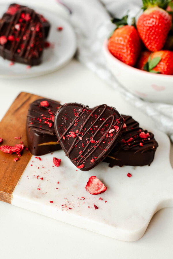 Stacked homemade heart shaped peanut butter cups garnished with freeze-dried strawberries.