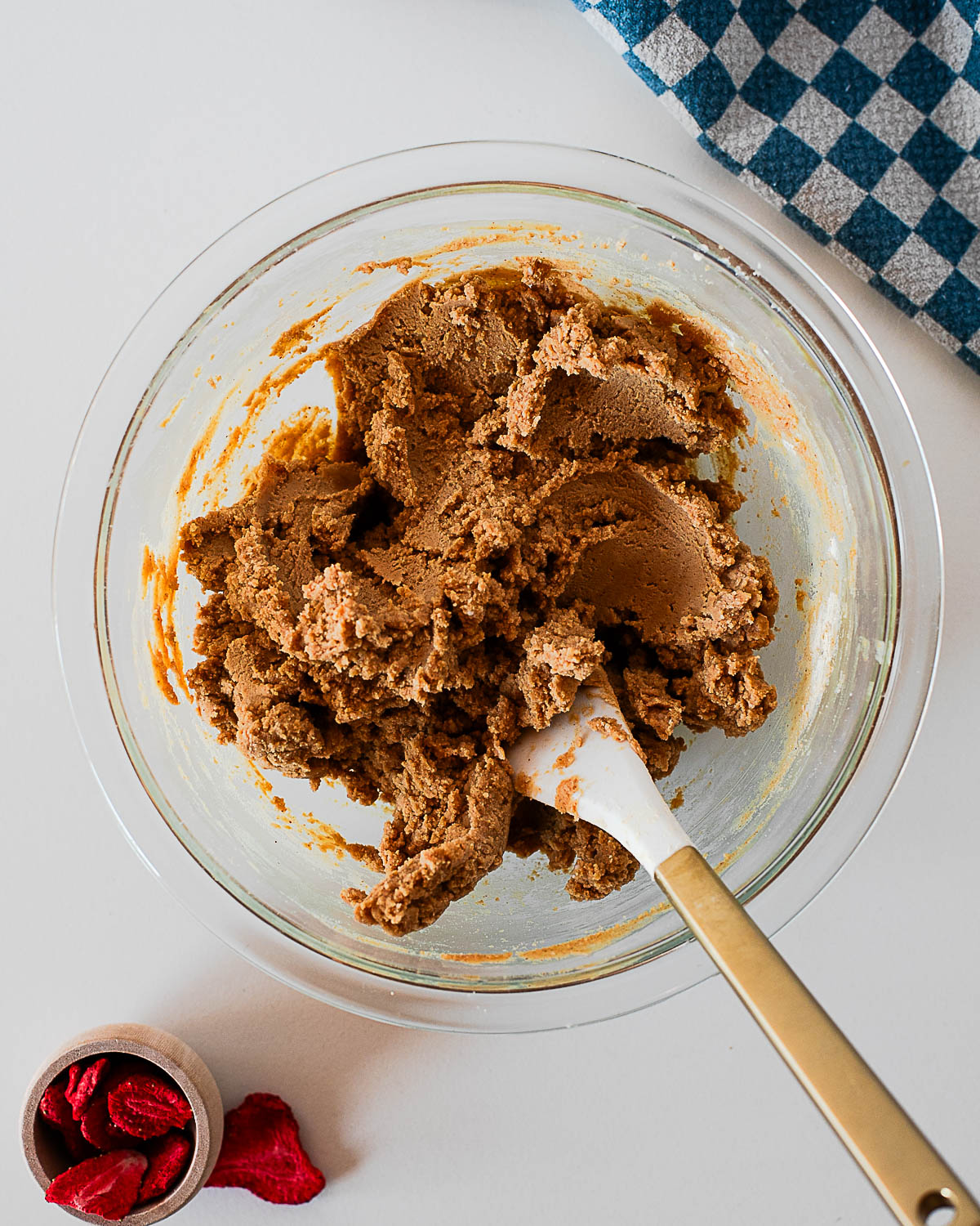 Thick peanut butter protein fudge mixture being stirred in a glass bowl with a spatula.