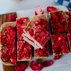 Overhead view of sliced peanut butter protein fudge with crushed freeze-dried strawberries scattered on top.