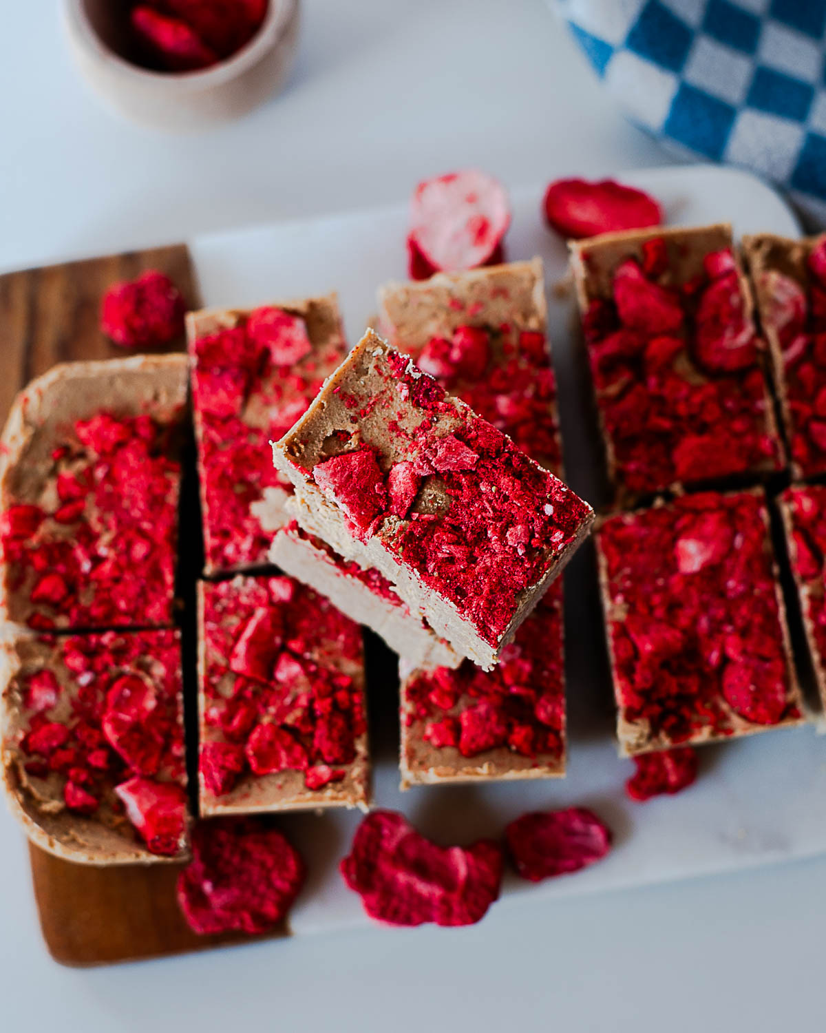 Overhead view of sliced peanut butter protein fudge with crushed freeze-dried strawberries scattered on top.