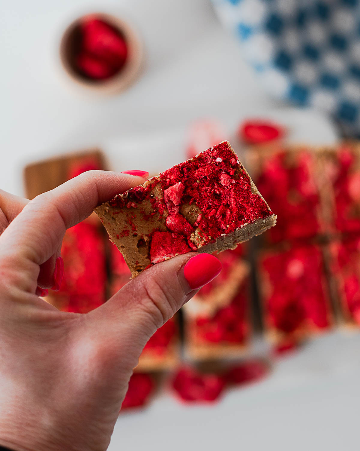Hand holding a square of PB&J protein fudge with peanut butter base and freeze-dried strawberry topping.