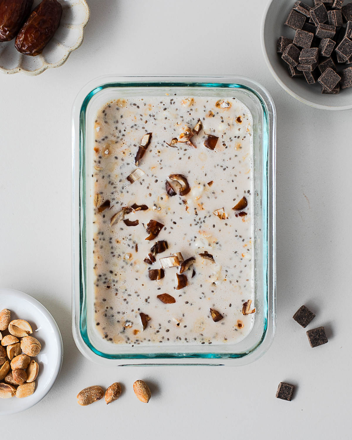 Overnight oats with chia seeds and chopped dates mixed into a creamy base in a glass meal prep container