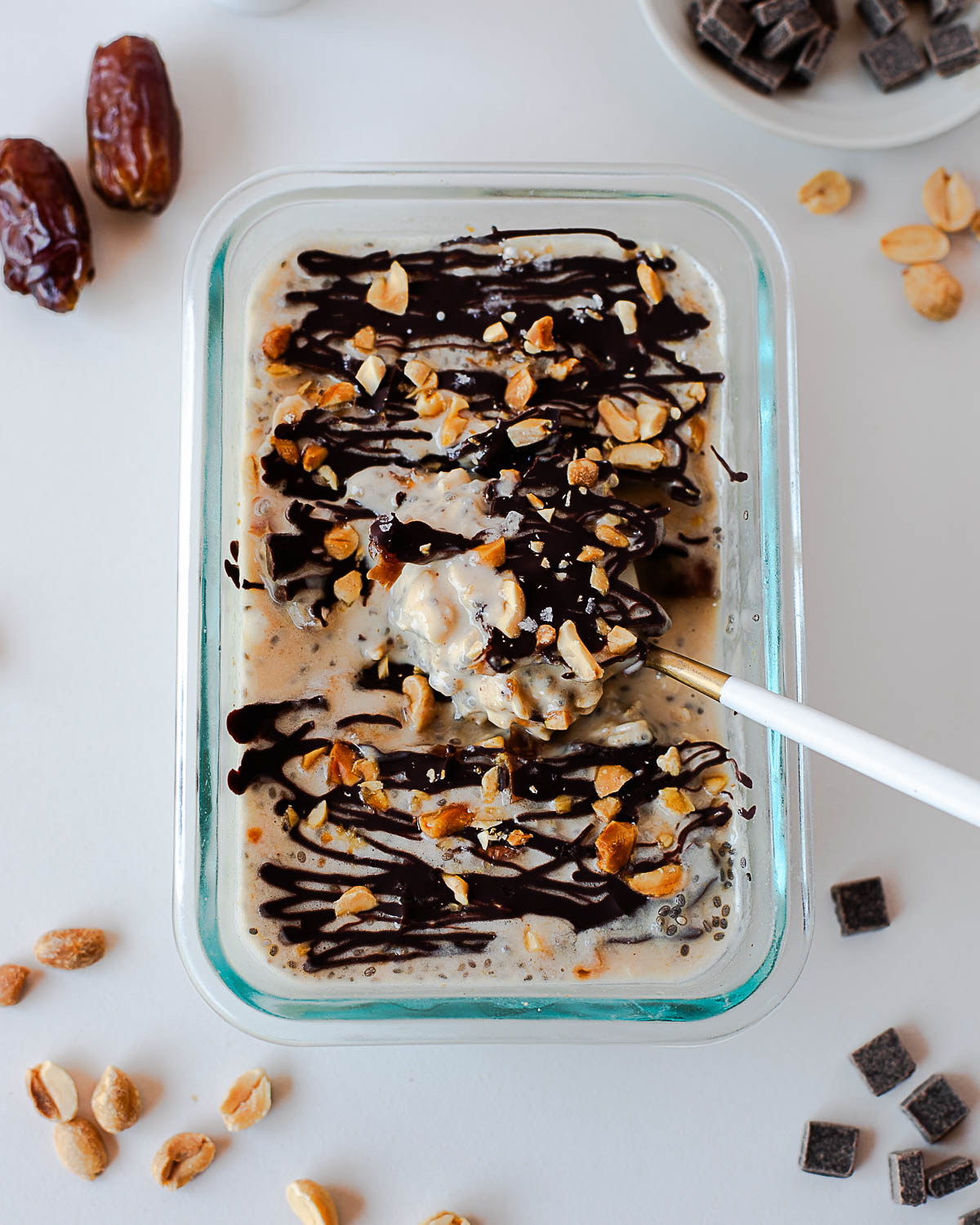Spoonful of Snickers overnight oats showing creamy oats, chocolate shell, peanuts, and date pieces