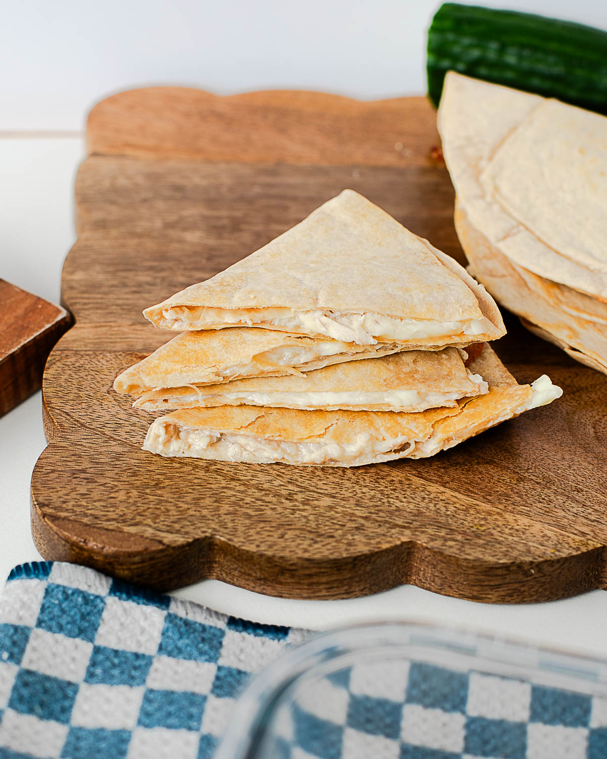 Stacked tuna melt quesadilla wedges on a wooden cutting board, lightly golden and crisp.
