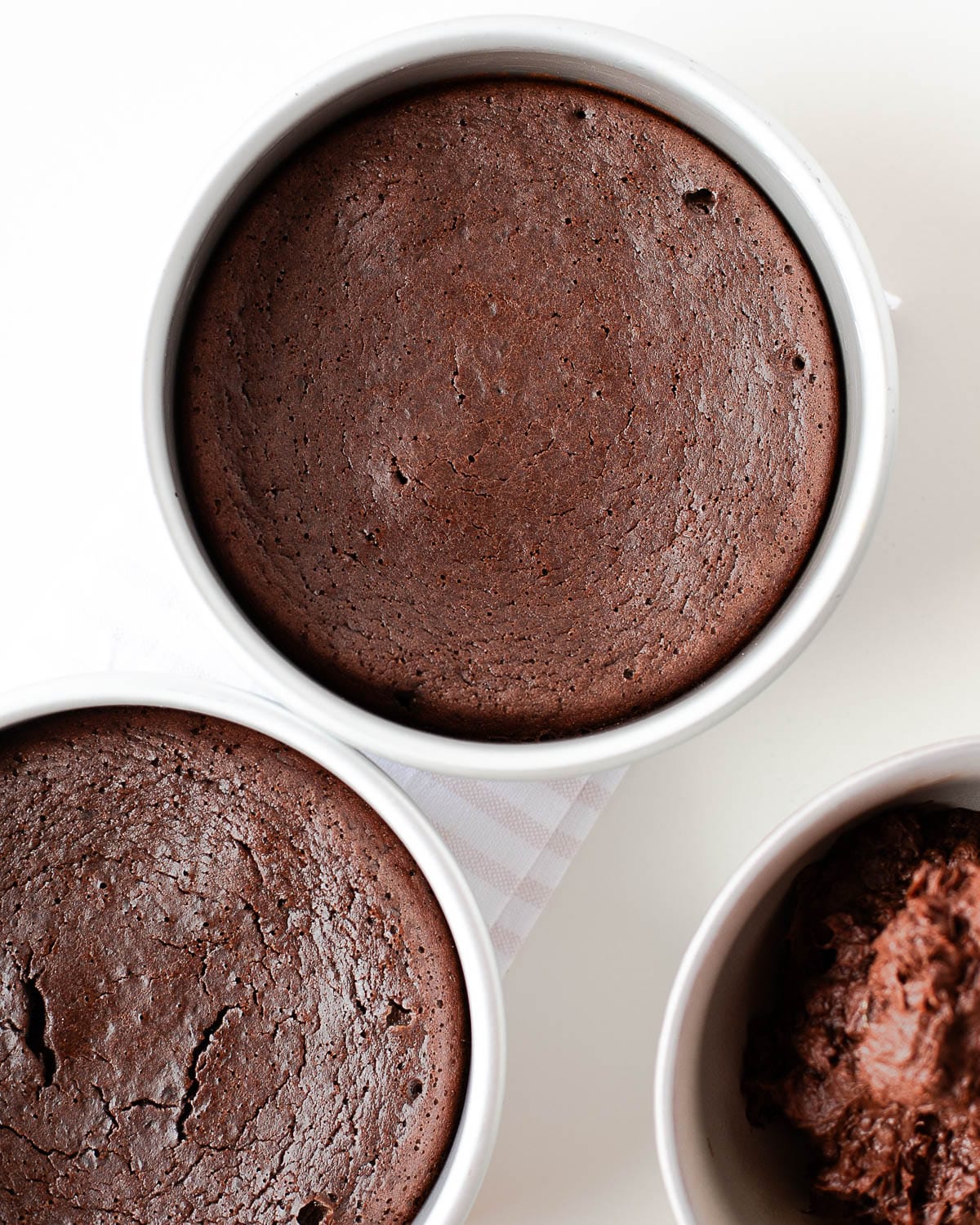 Freshly baked flourless black bean chocolate cake layers cooling in round cake pans.