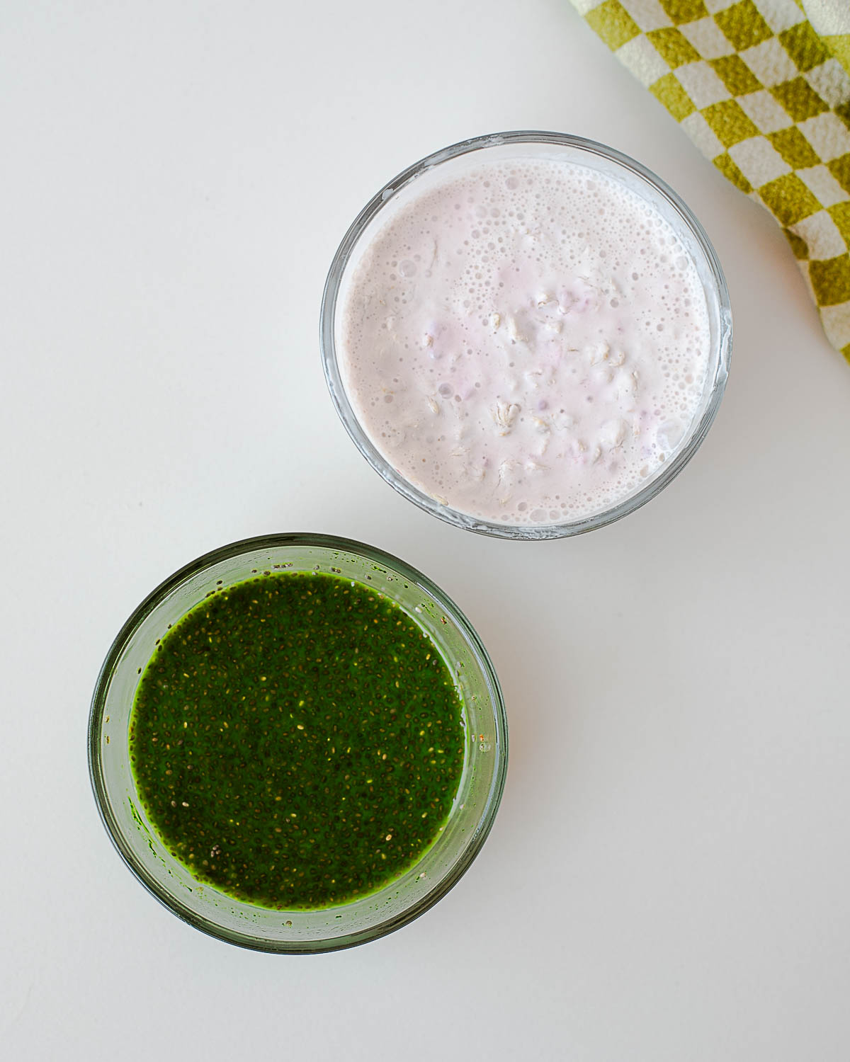 Prepared raspberry overnight oats and matcha chia pudding in glass bowls before layering, showing creamy oat mixture and vibrant green chia pudding.