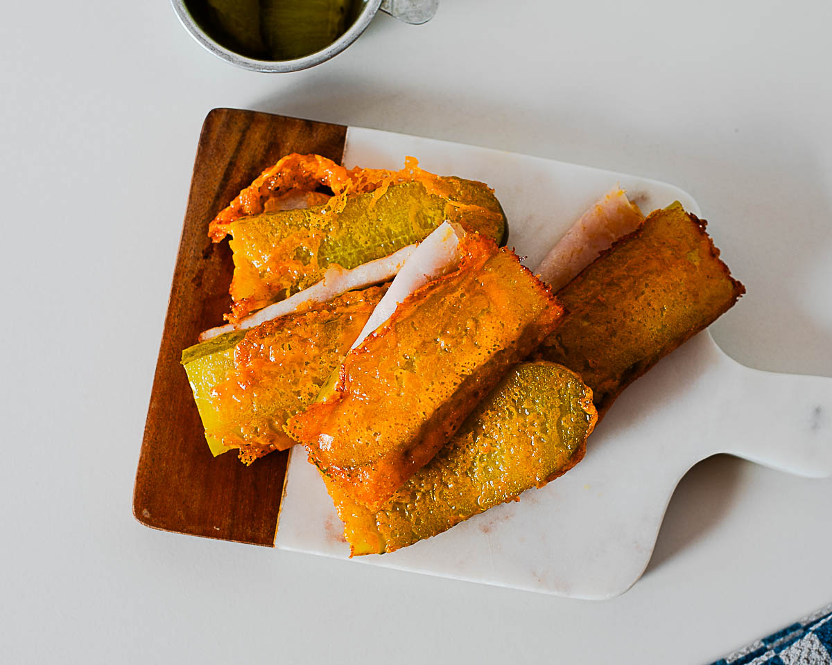 Overhead view of homemade chickles served on a cutting board with pickles in the background