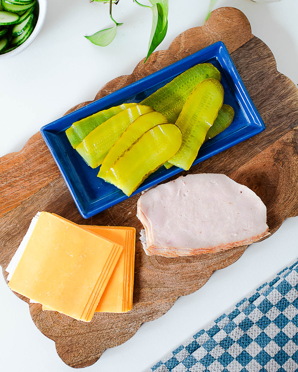 Ingredients for chickles including sliced cheddar cheese, deli turkey, and dill pickle slices on a board