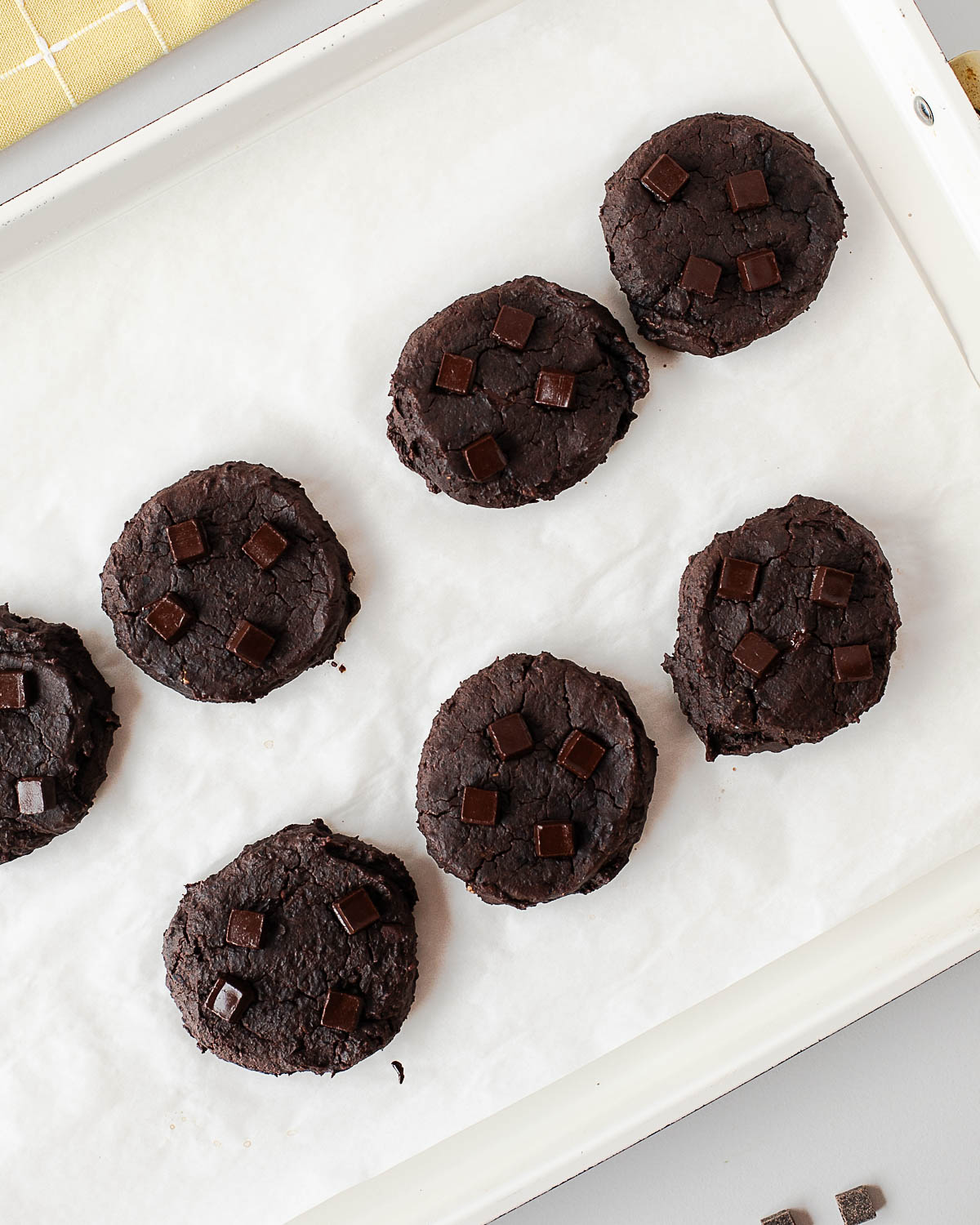 Baked black bean cookies with dark chocolate chunks on a baking tray
