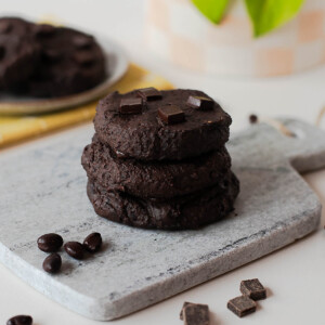Stack of fudgy chocolate black bean cookies on a stone board with chocolate pieces