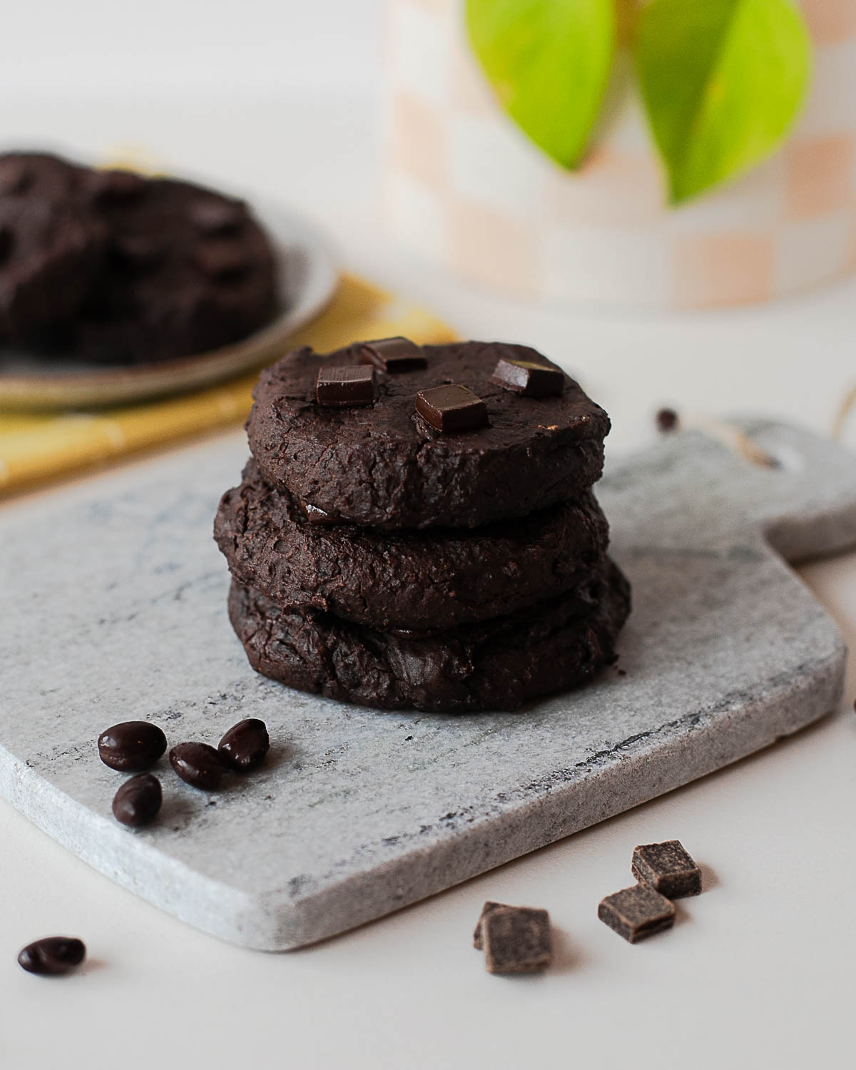Stack of fudgy chocolate black bean cookies on a stone board with chocolate pieces