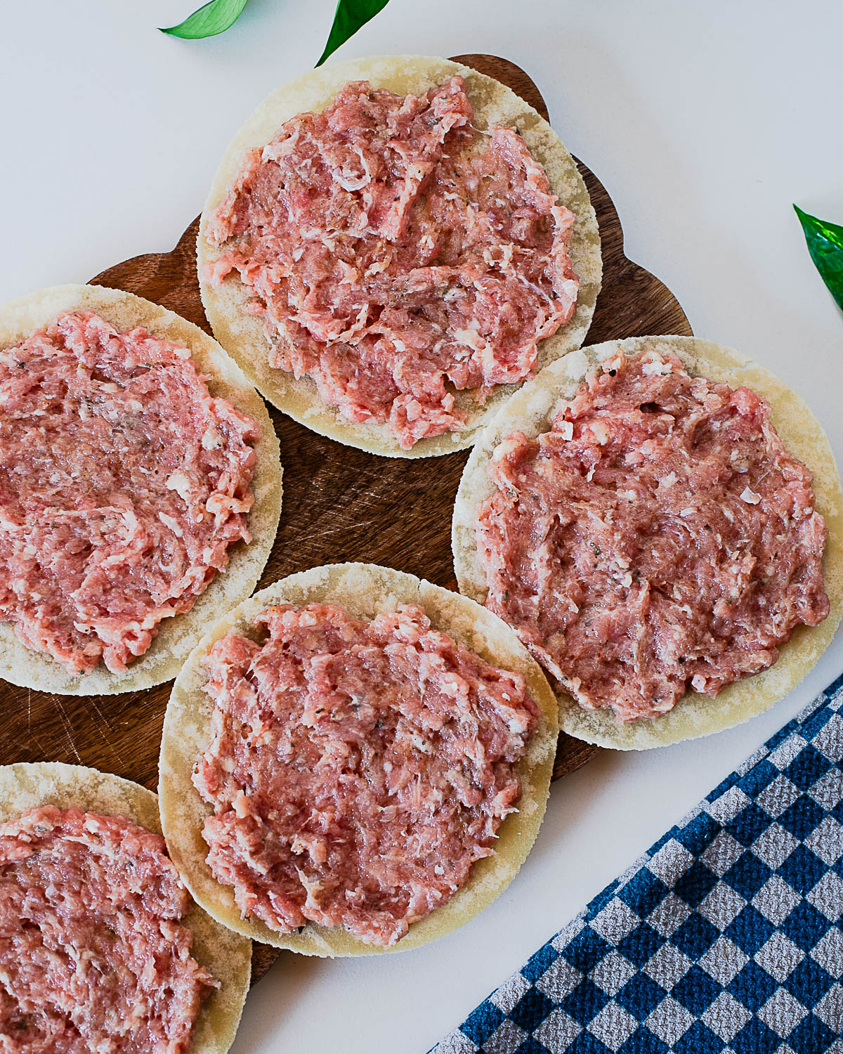 Ground chicken pressed onto small tortillas to make chicken caesar smash tacos before cooking.