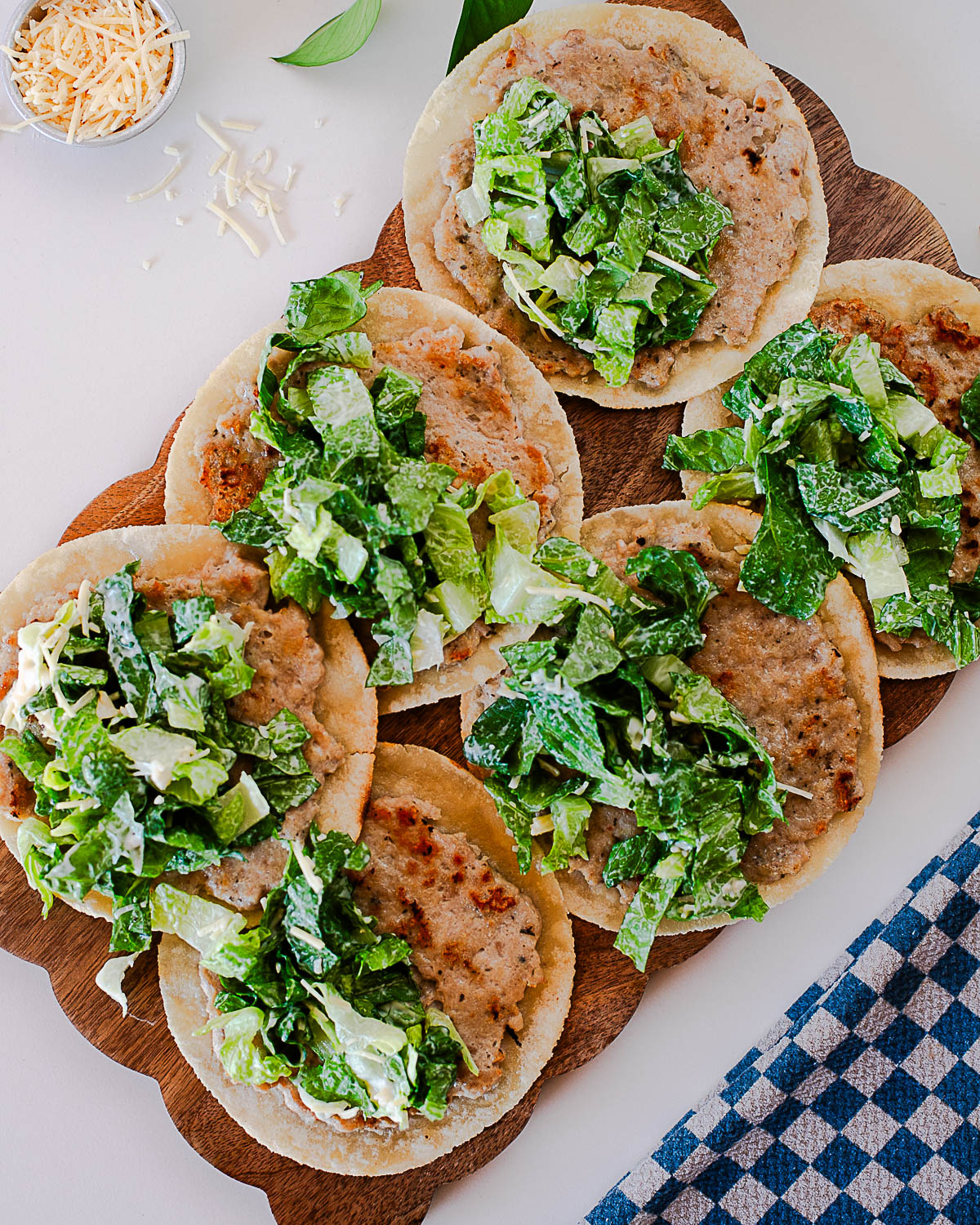 Chicken caesar smash tacos topped with romaine lettuce and creamy caesar dressing on a wooden board.