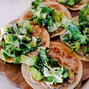 Close-up of crispy chicken caesar smash tacos with chopped romaine and parmesan cheese.