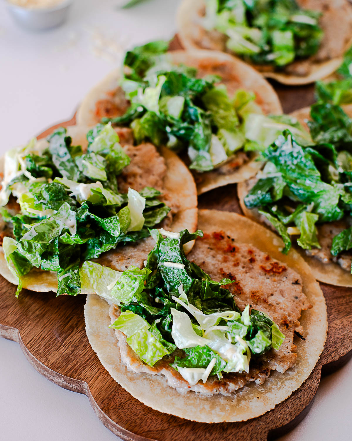 Close-up of crispy chicken caesar smash tacos with chopped romaine and parmesan cheese.