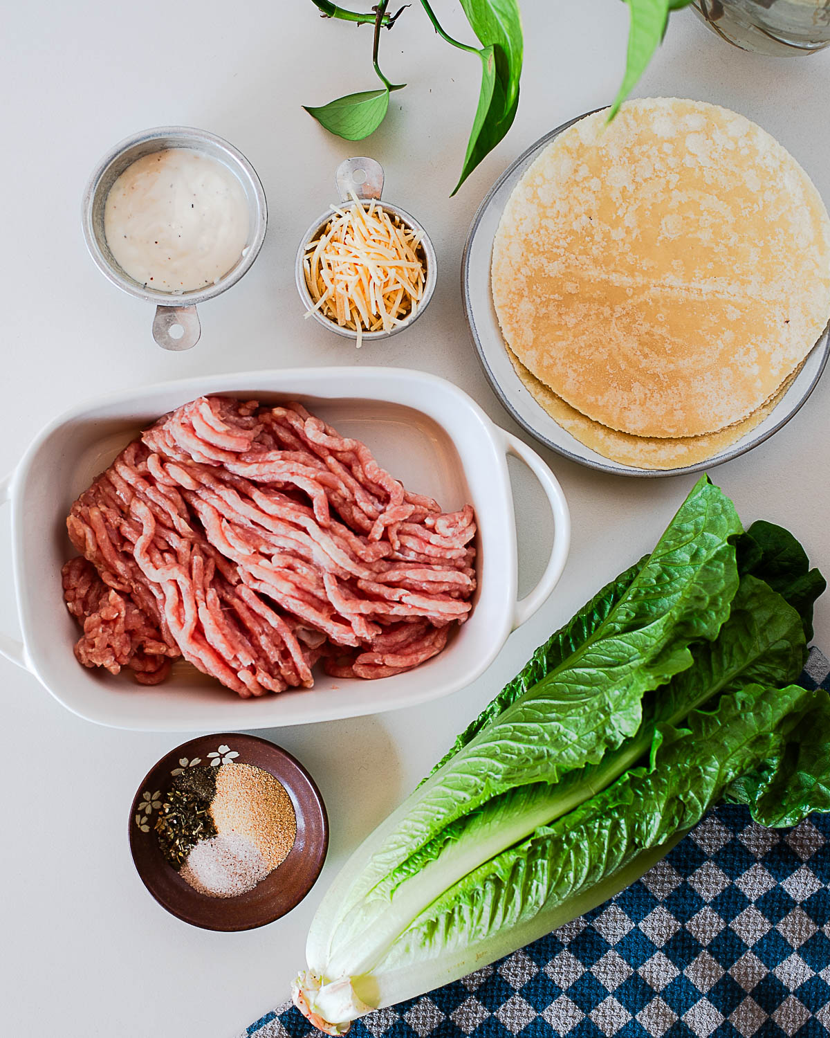 Ingredients for chicken caesar smash tacos including ground chicken, romaine lettuce, tortillas, caesar dressing, and parmesan.
