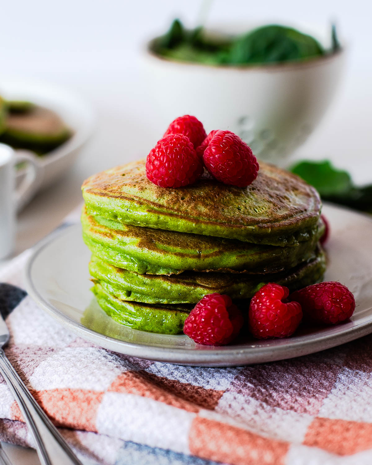 Stack of healthy spinach pancakes with raspberries on top
