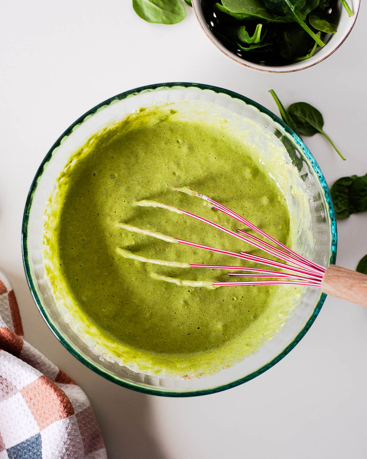 Green einkorn pancake batter with spinach being whisked in a glass bowl