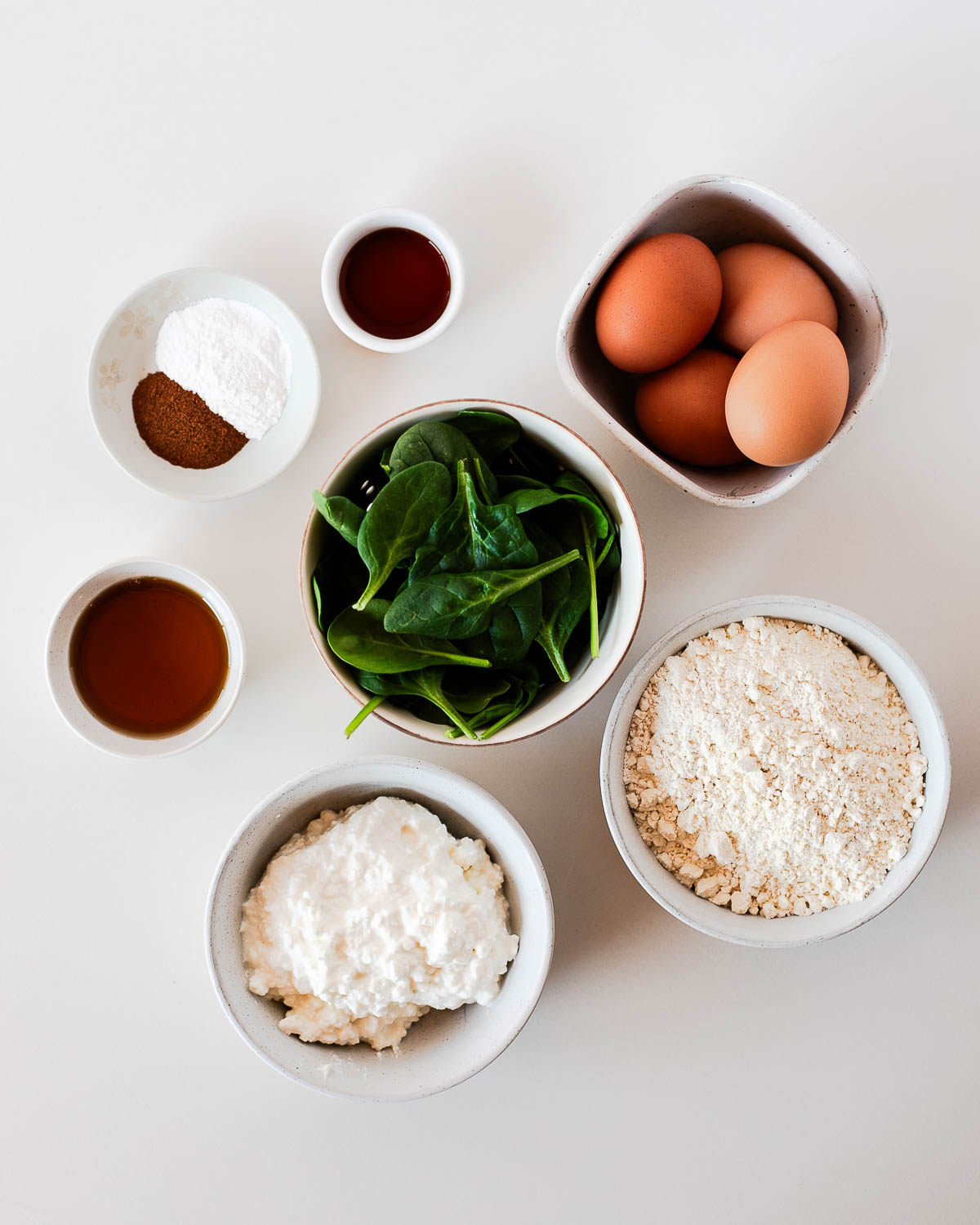 Ingredients for einkorn spinach pancakes including eggs, spinach, cottage cheese, and flour