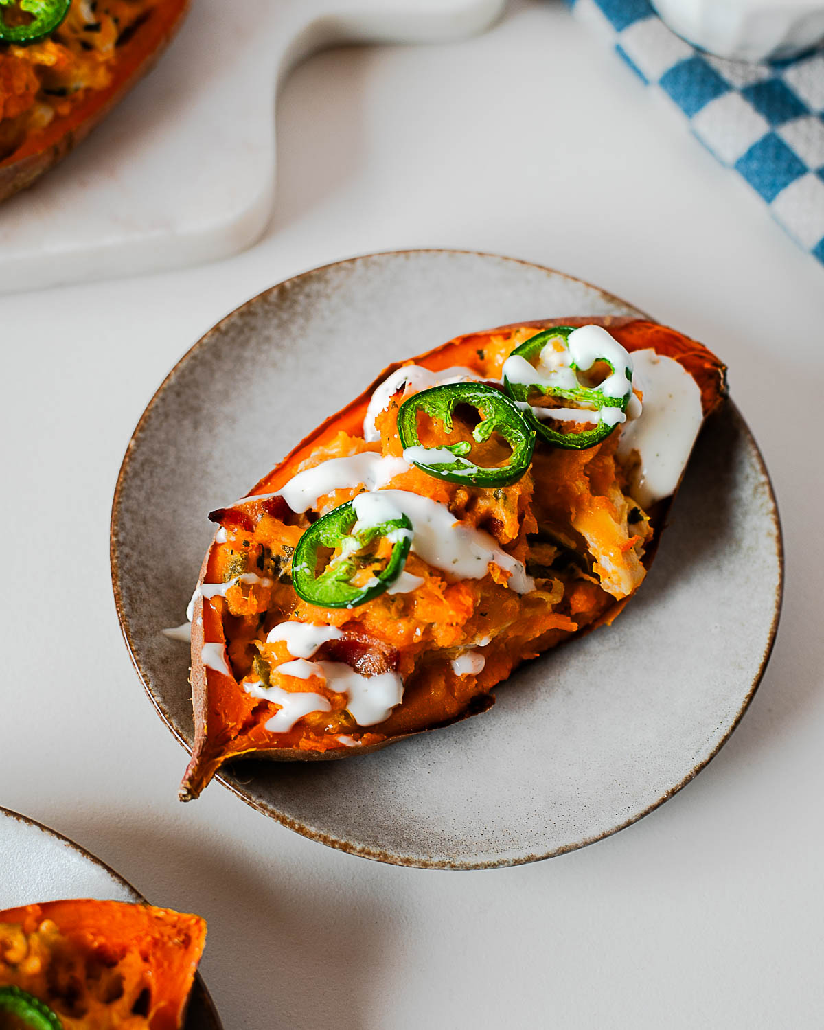 Sweet potato boat topped with jalapeños and creamy drizzle