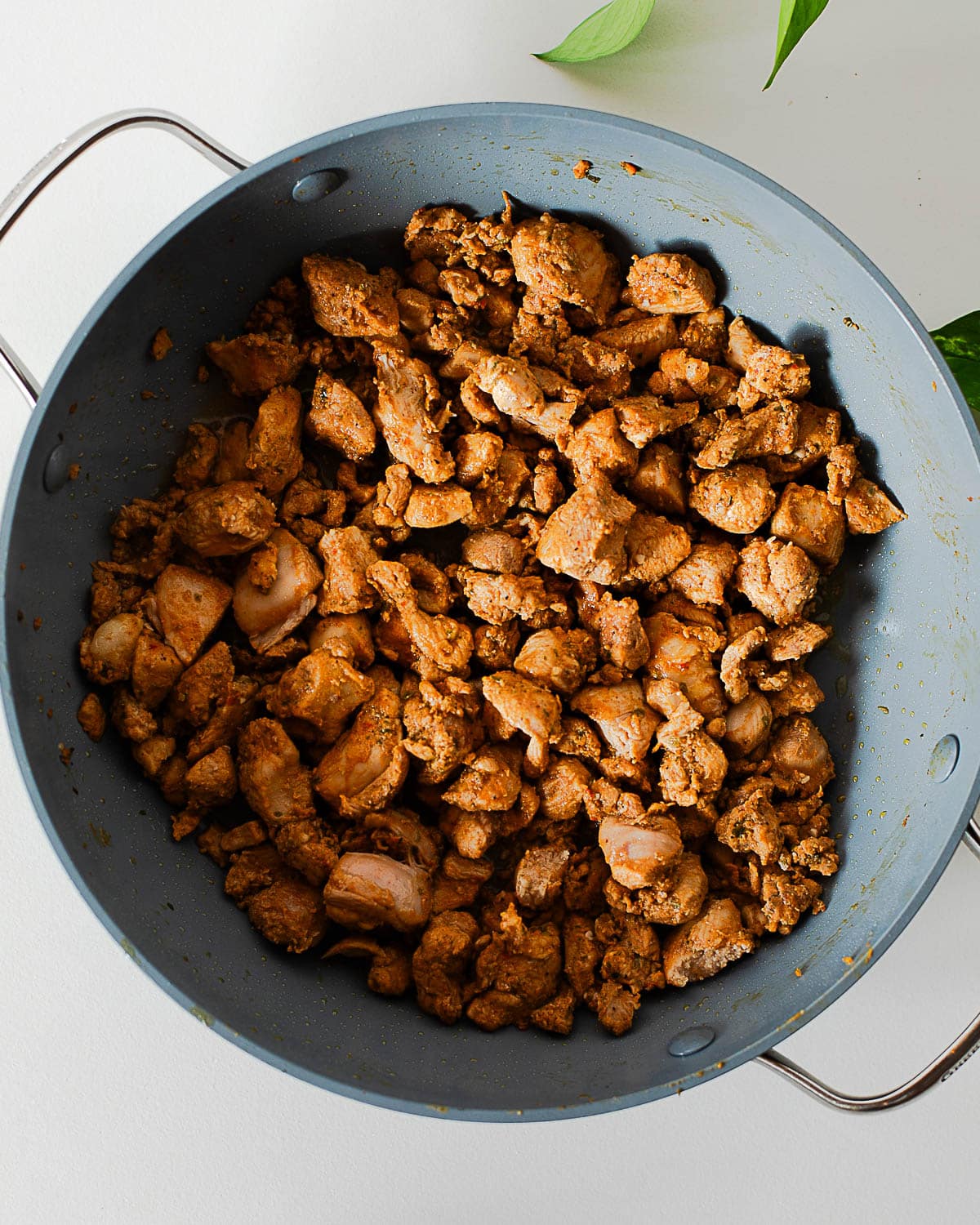 Diced Korean BBQ chicken cooking in a skillet until golden brown for Korean BBQ chicken bowls.