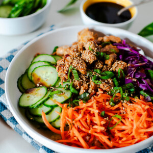 Balanced Korean BBQ chicken bowl with fresh veggies and sesame seeds served over cauliflower rice.