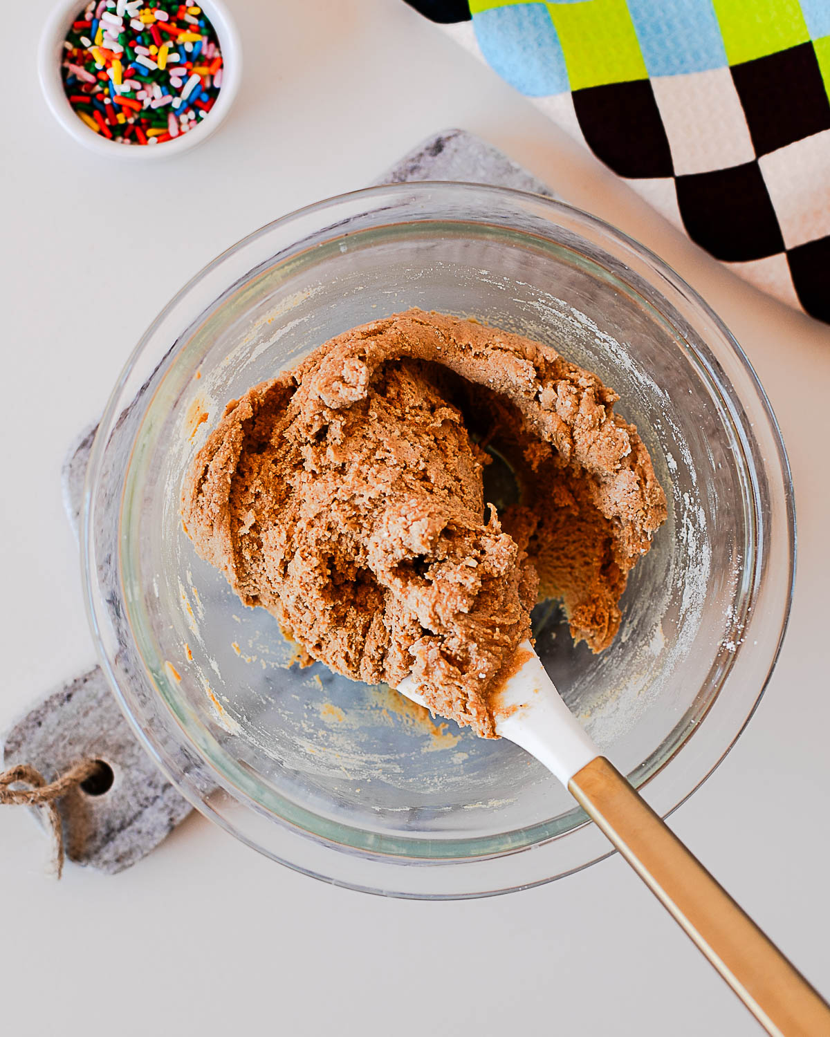 Thick protein ball dough mixed in a glass bowl with a spatula, ready for sprinkles.