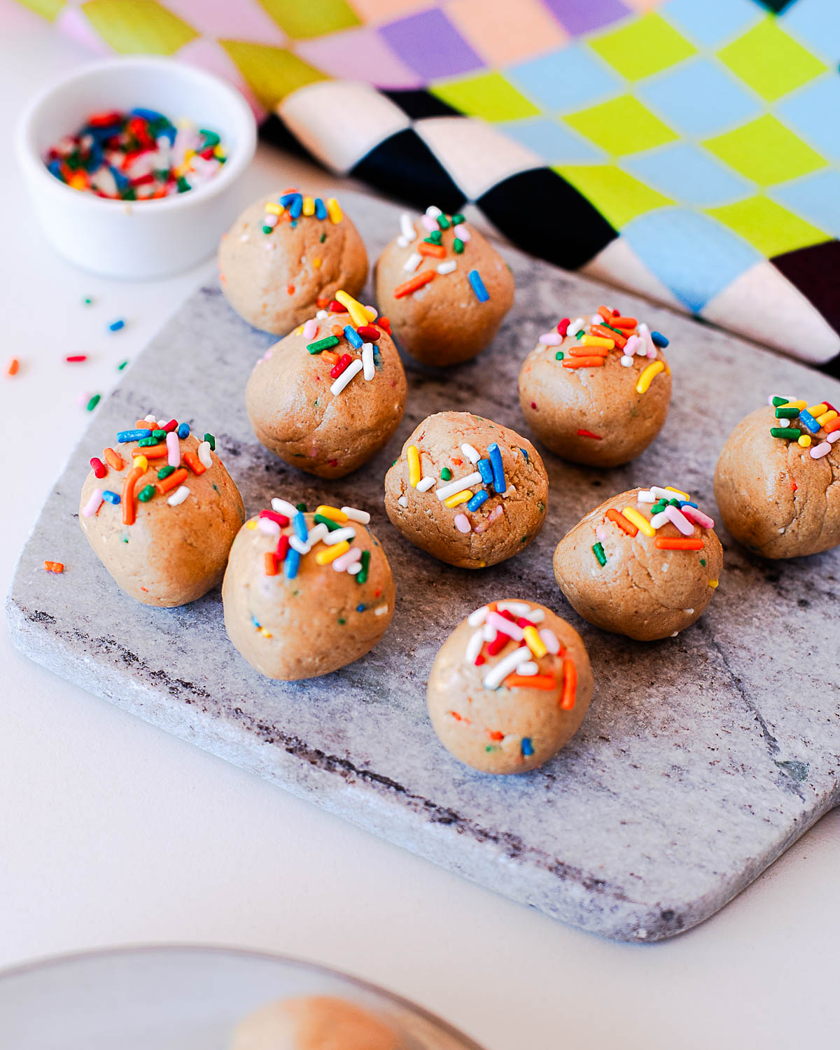 High-protein birthday cake energy bites arranged on a marble cutting board.