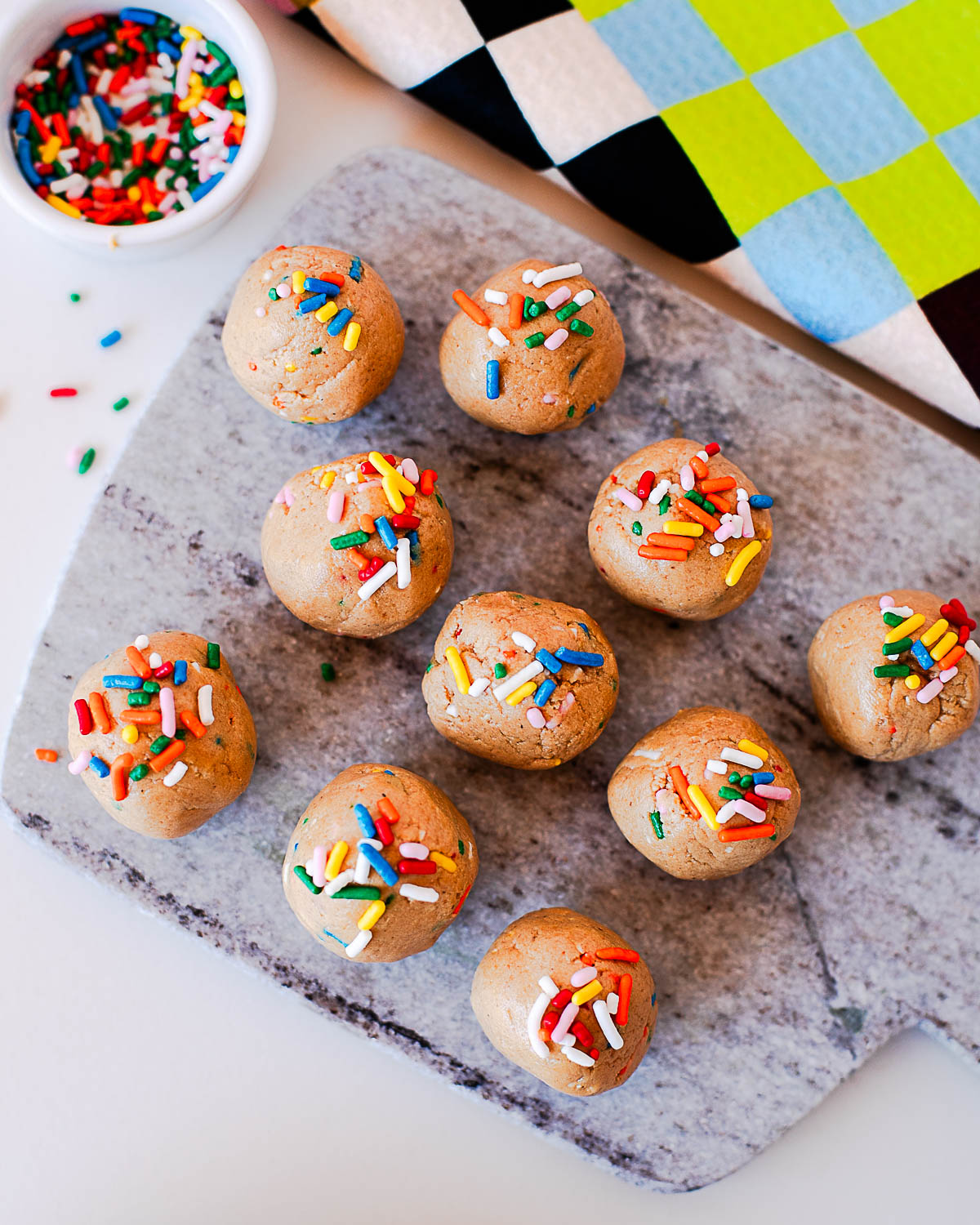 Overhead view of homemade birthday cake protein balls with sprinkles on a serving board.