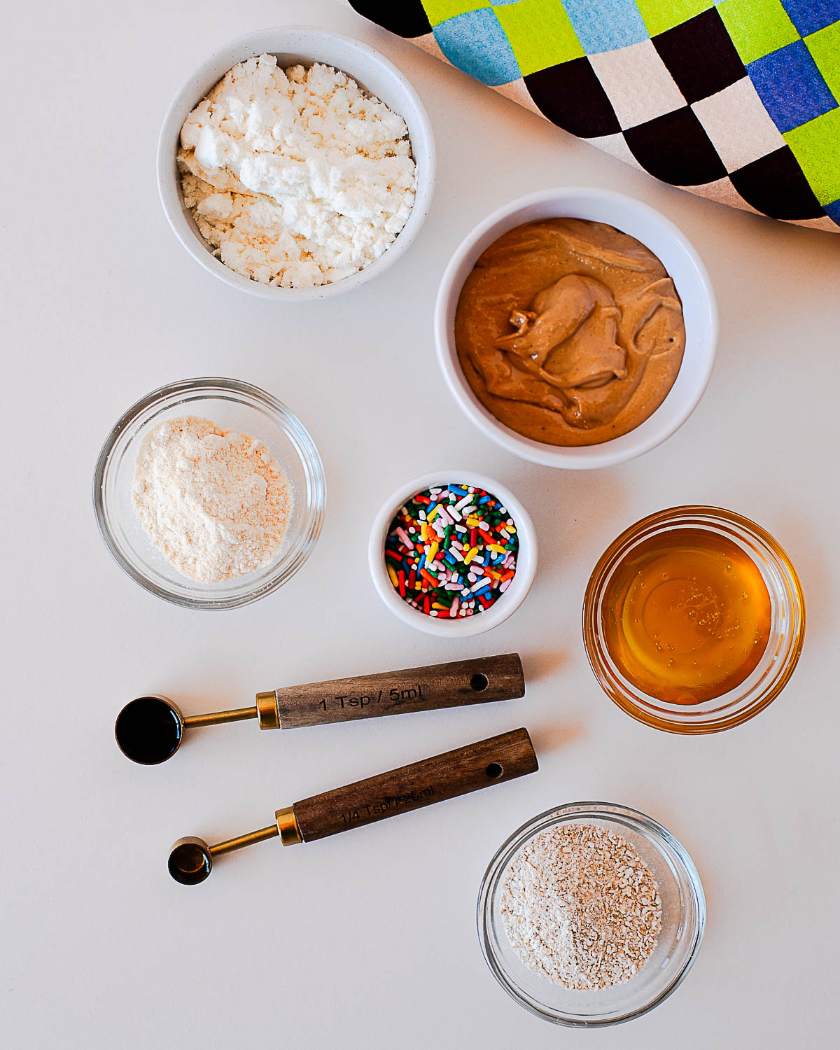 Ingredients for birthday cake protein balls including protein powder, cashew butter, oat flour, honey, and sprinkles.