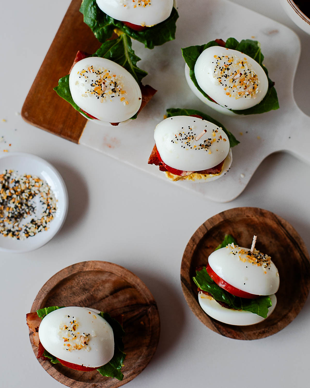 Platter of BLT deviled egg sliders with bacon, lettuce, and tomato on a wooden serving board