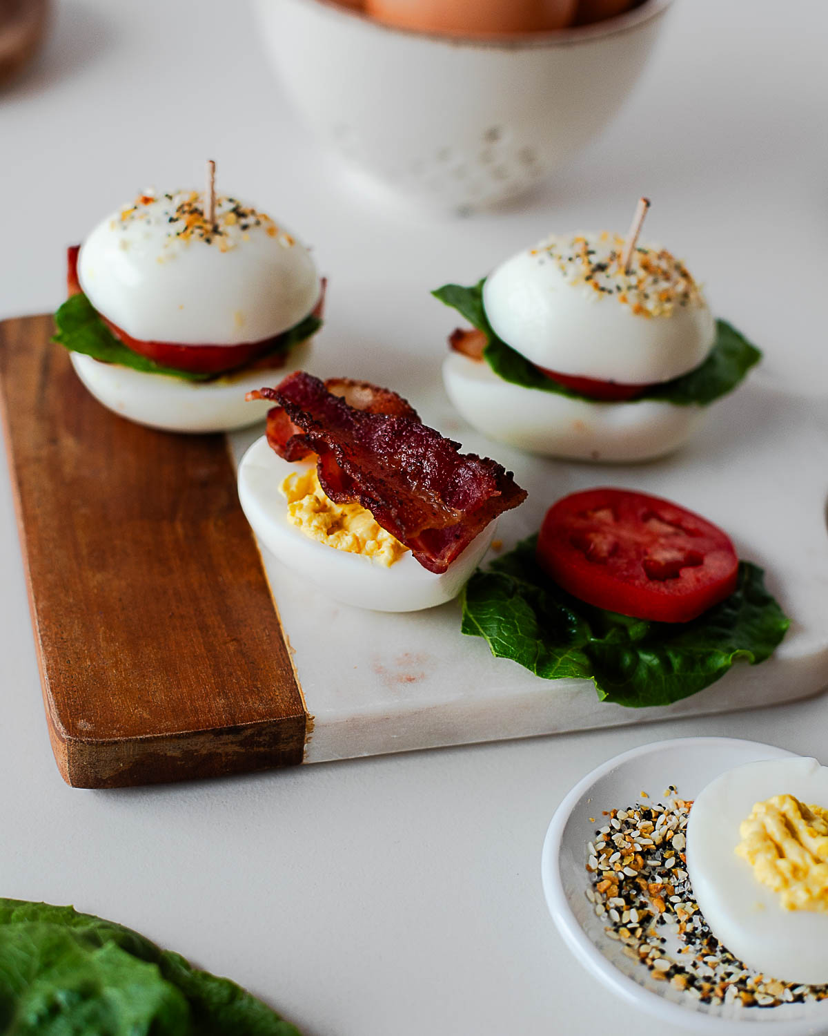 Deviled egg halves layered with crispy bacon, lettuce, and tomato to create BLT egg sliders