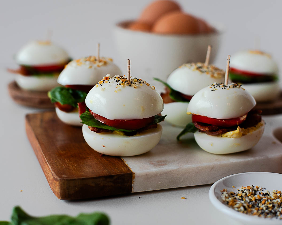 Deviled egg halves layered with crispy bacon, lettuce, and tomato to create BLT egg sliders