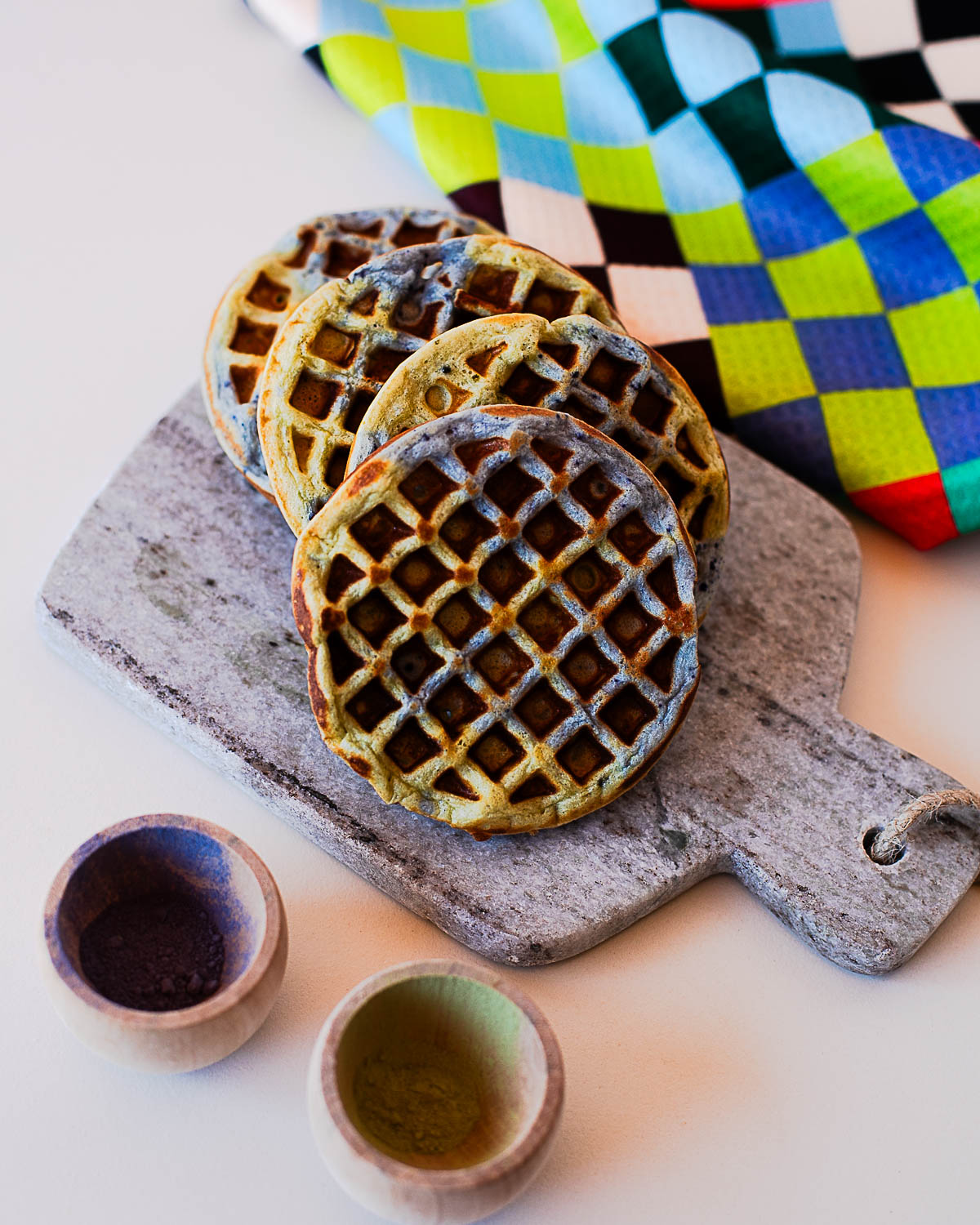 Stack of Earth Day waffles with blue and green swirls on a stone board with natural powders