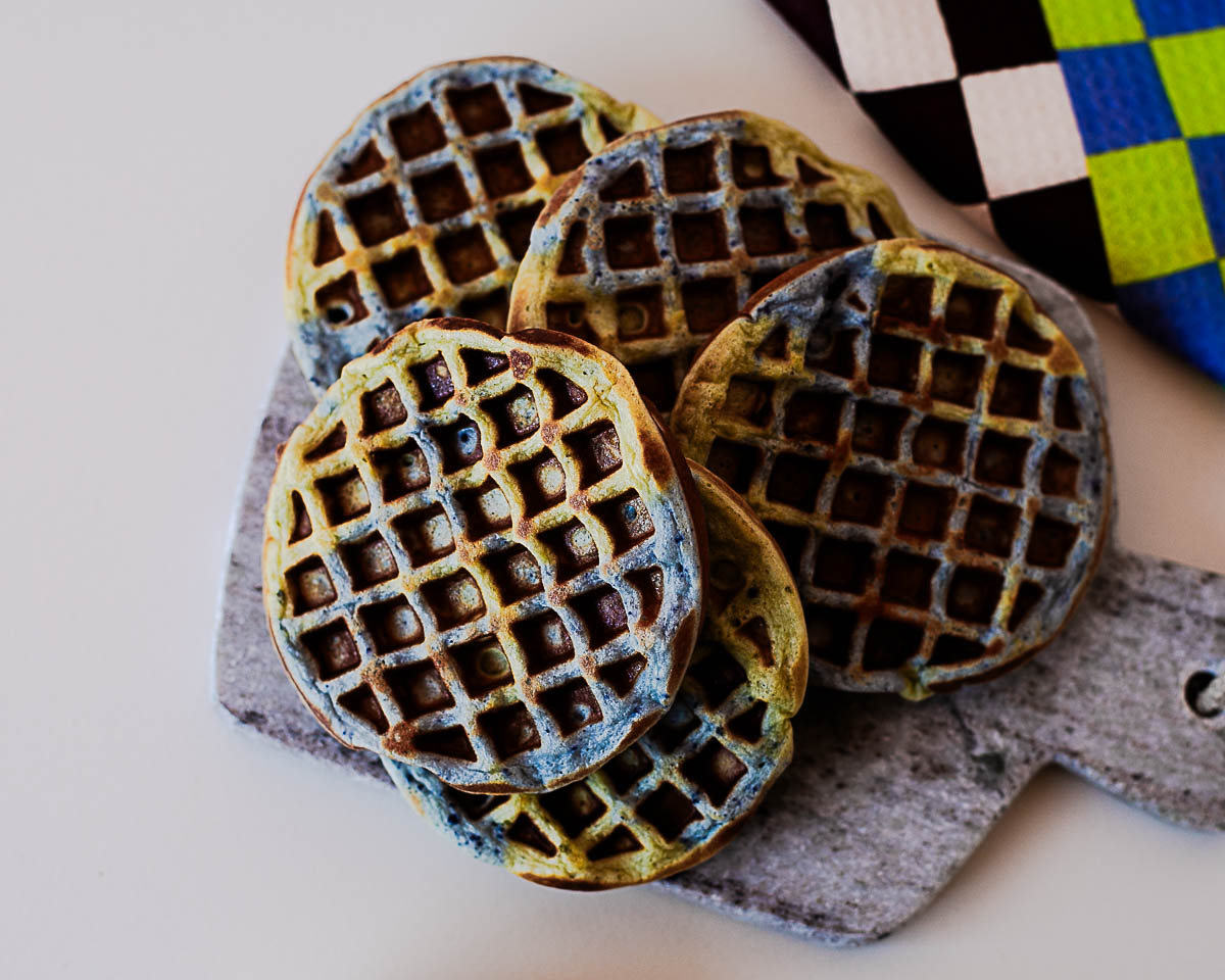 Stack of Earth Day waffles with blue and green swirls on a stone board with natural powders