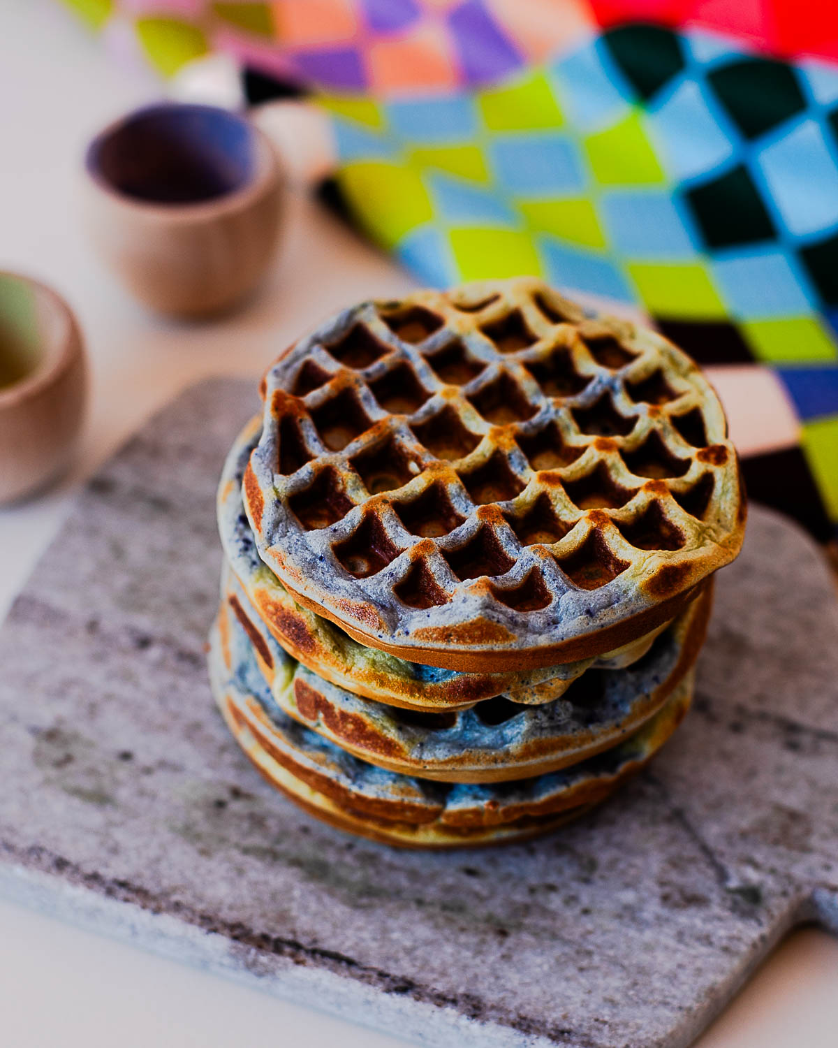 Stack of crispy Earth Day waffles with natural colors served on a stone board