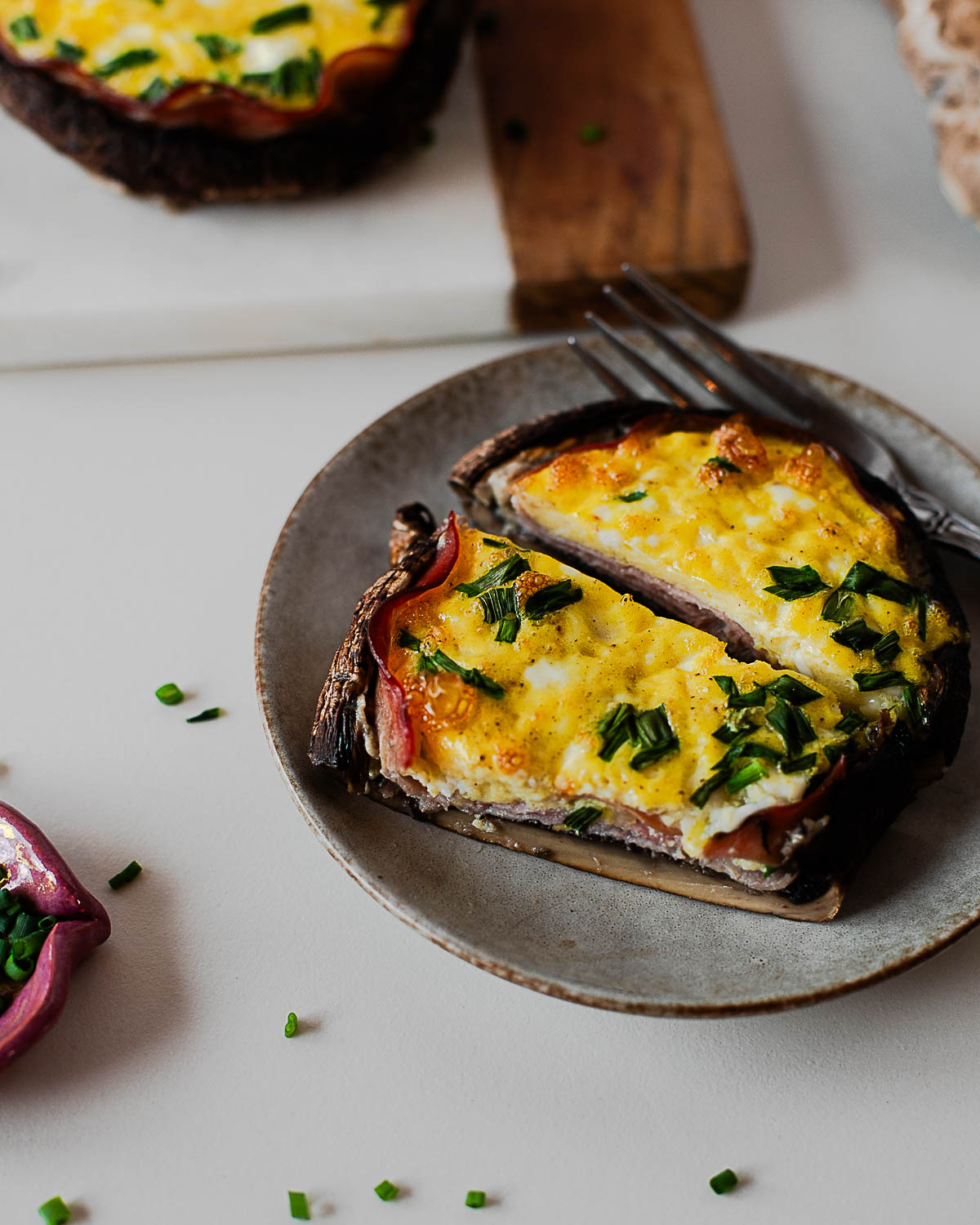 Close-up of a stuffed portobello mushroom with fluffy baked eggs and herbs