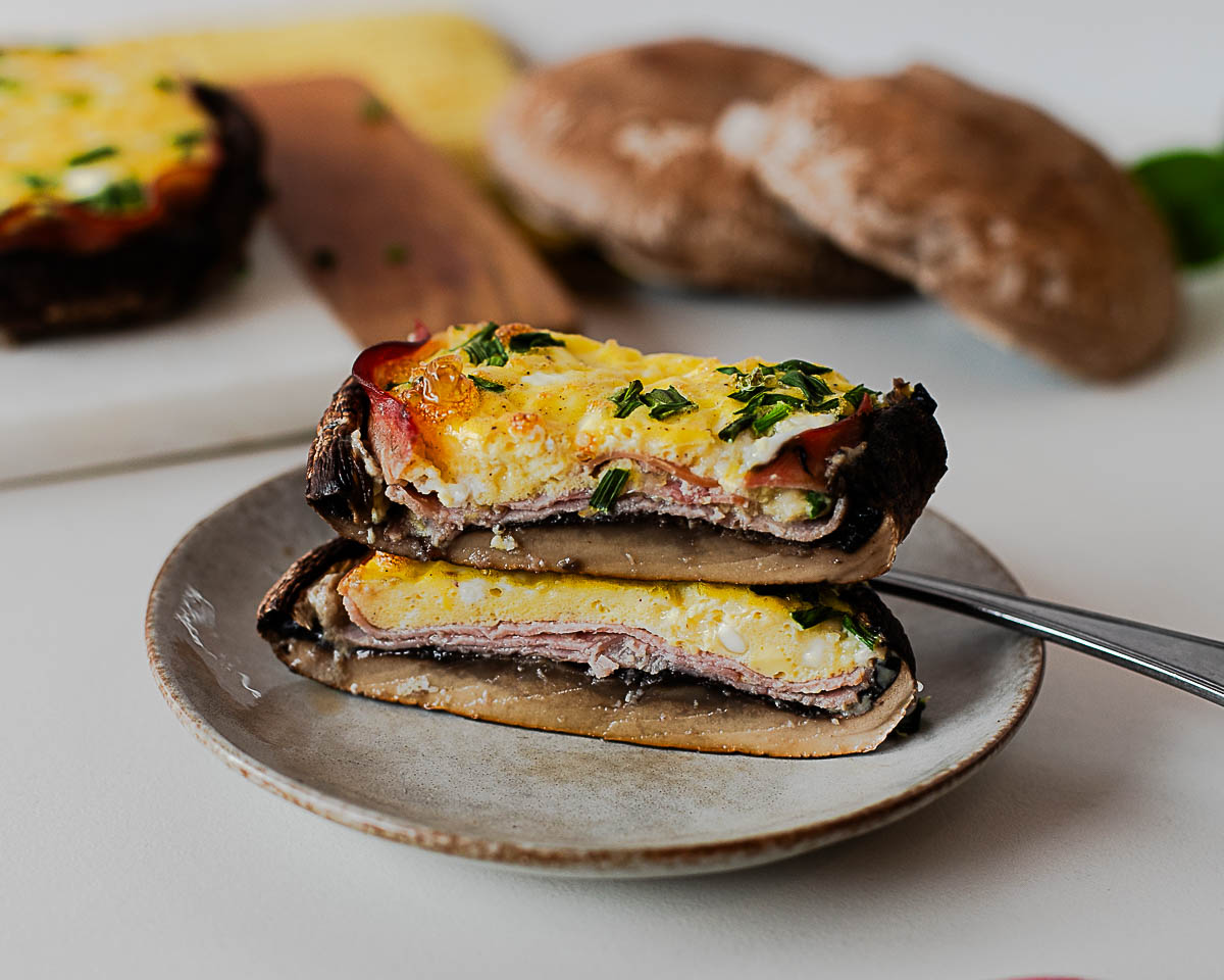 Side view of sliced portobello mushroom breakfast with eggs, ham, and chives on a plate