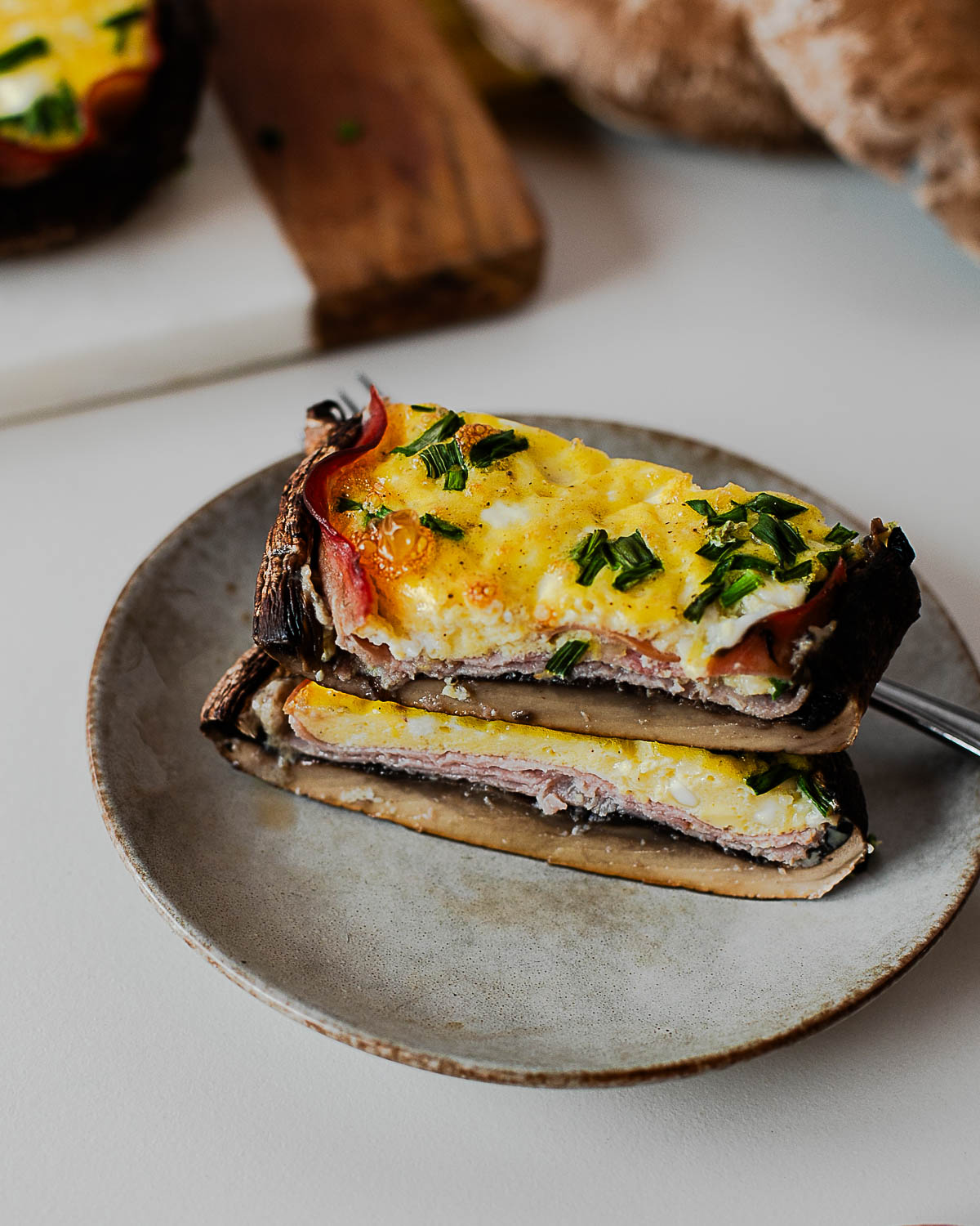 Angled view of baked egg stuffed portobello mushroom caps with golden tops and herbs