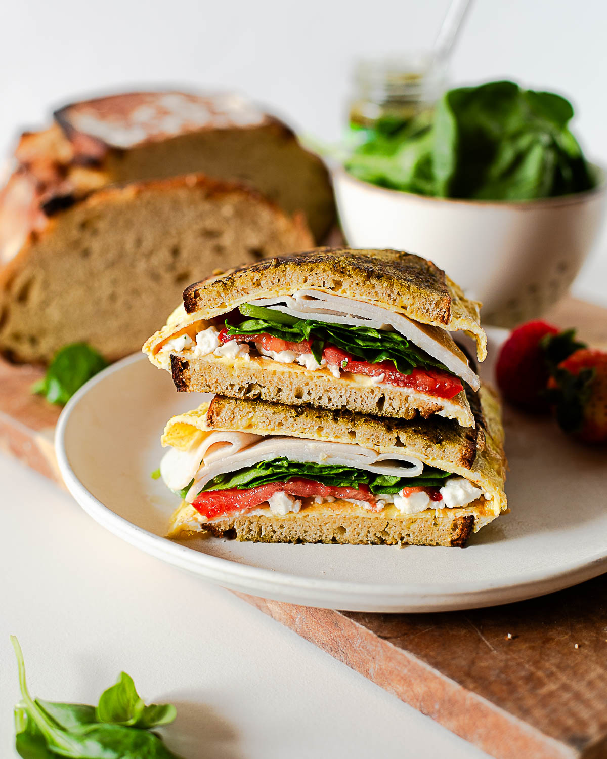 Crispy pesto breakfast sandwich with fluffy eggs cooked into bread, layered with feta, turkey, spinach, and tomato