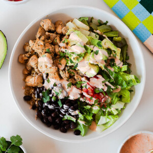 Southwest chicken burrito bowl with quinoa, black beans, avocado, lettuce, pico de gallo, and creamy spicy ranch drizzle.