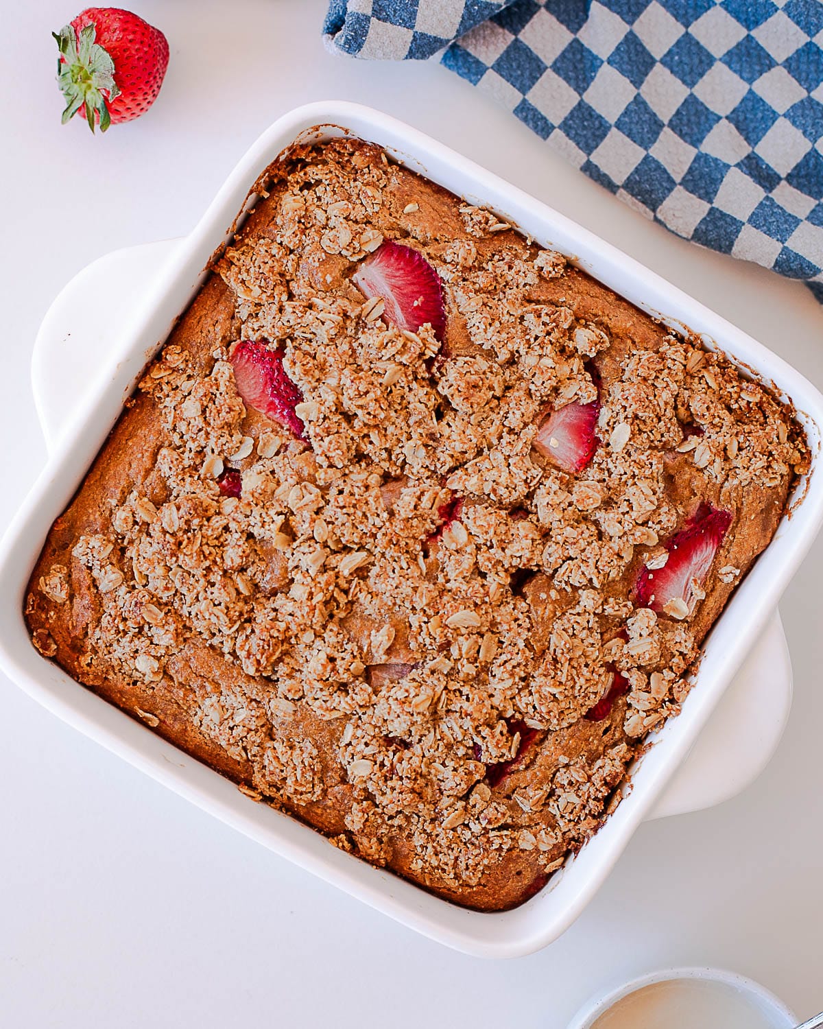 Overhead view of baked strawberry coffee cake with oats crumble and visible strawberries