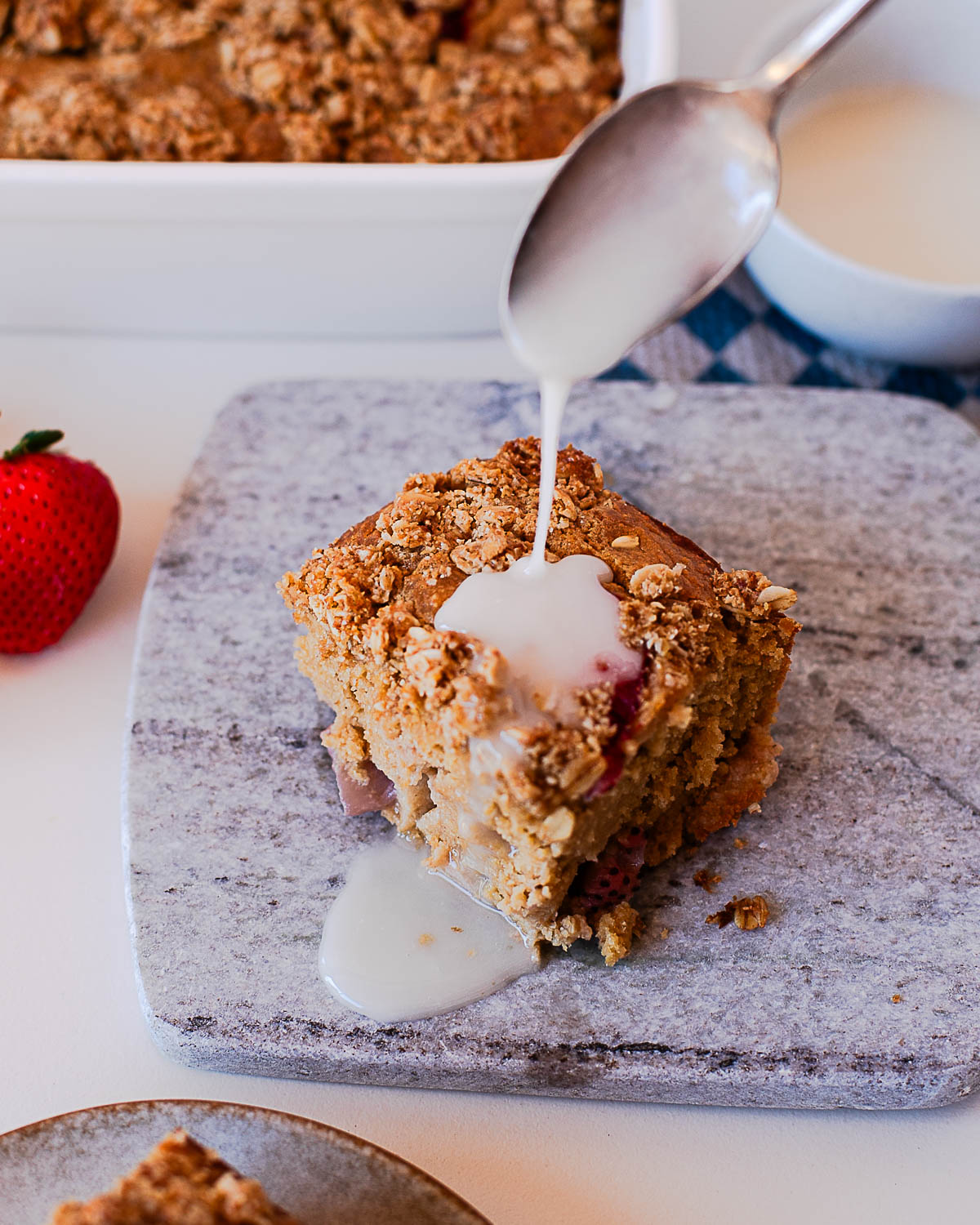 Close-up of strawberry crumb coffee cake slice on a plate with glaze drizzle